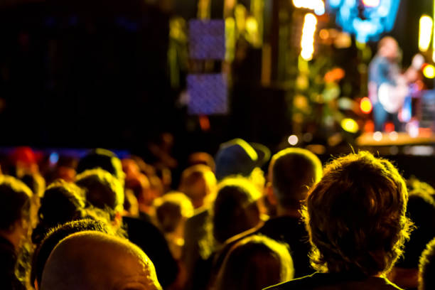 Crowd attending an outdoor rock show, taking pictures, having fun and dancing during a summer festival in the streets of Montreal.