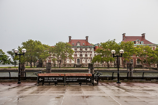 New York City, United States of America - July 27, 2018. A sign directs people to either a boat to NYC or a boat to Jersey City from Ellis Island on a rainy day.