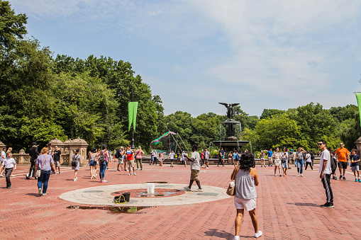 New York City, United States of America - July 28, 2018. People fill up the square around the iconic Bethesda Fountain in Central Park as a street performer makes large bubbles.