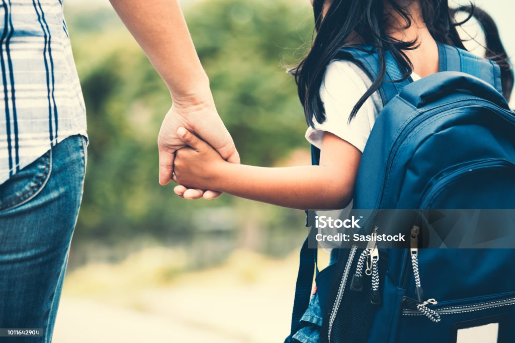Carina studentessa asiatica con zaino che tiene la mano della madre e va a scuola - Foto stock royalty-free di Bambino