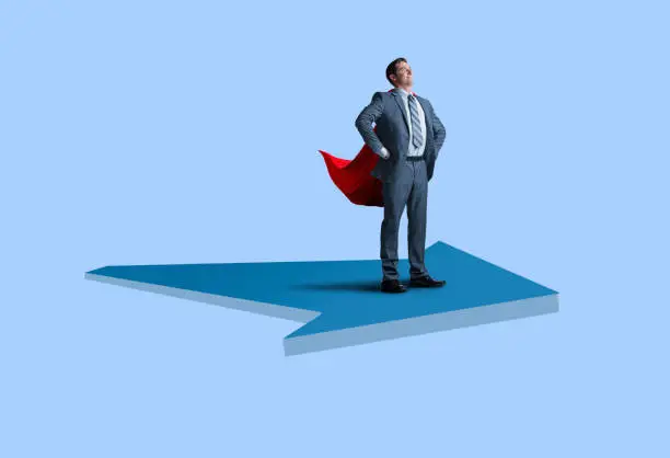 Photo of Businessman Super Hero With Cape Rides Large Arrow On Blue Background