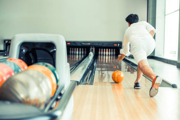 joven jugando bowling. - bowling holding bowling ball hobbies fotografías e imágenes de stock