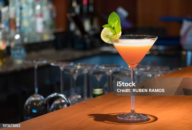 Photo libre de droit de Un Verre De Martini De Couleur Orange Sur Le Comptoir En Bois banque d'images et plus d'images libres de droit de Martini dry