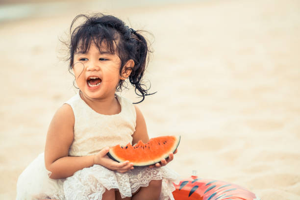 istock Adorable kid eating watermelon on the beach. 1011673140