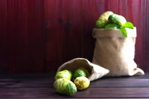 Noni in sack and noni with leaves on wooden table and wooden background Noni in sack and noni with leaves on wooden table and wooden background1 noni fruit stock pictures, royalty-free photos & images