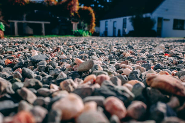 Red Gravel Low angle shot of gravel on a drive way that is red and grey with a white house in the back ground slightly out of focus. pebble driveway stock pictures, royalty-free photos & images