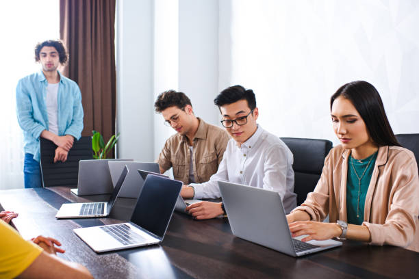 istock multiethnic group of business partners working at table with laptops in modern office 1011723858