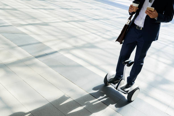 Businessman on hoverboard Businessman checking text messages, drinking take-out coffee and riding hoverboard hoverboard stock pictures, royalty-free photos & images