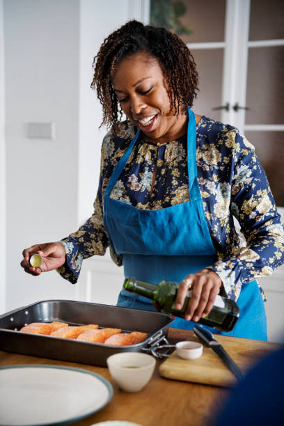 Woman adding spices and herb to raw salmon