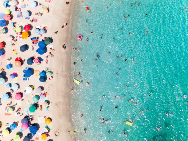 Photo of View from above, aerial view of an emerald and transparent Mediterranean sea with a white beach full of beach umbrellas and tourists who relax and swim. Costa Smeralda, Sardinia, Italy.