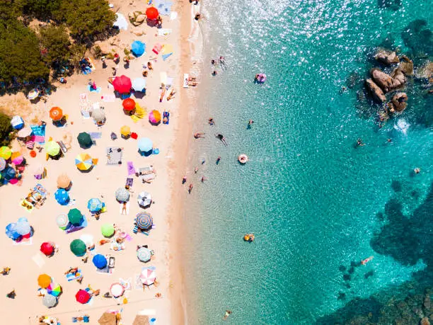 Photo of View from above, aerial view of an emerald and transparent Mediterranean sea with a white beach full of beach umbrellas and tourists who relax and swim. Costa Smeralda, Sardinia, Italy.