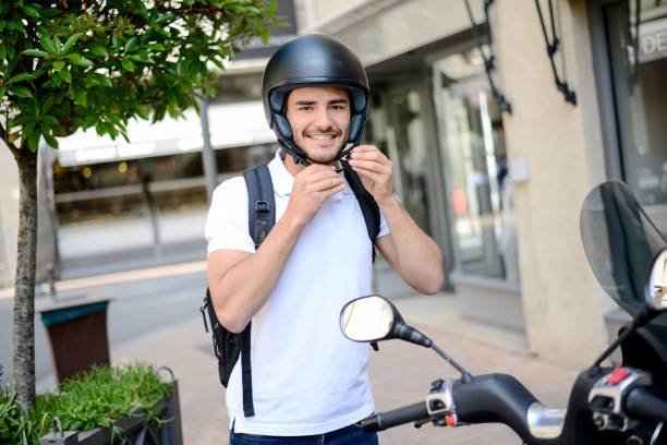 hübscher junger mann in einer modernen stadt anpassen motorradhelm im sommer - motorradfahrer stock-fotos und bilder