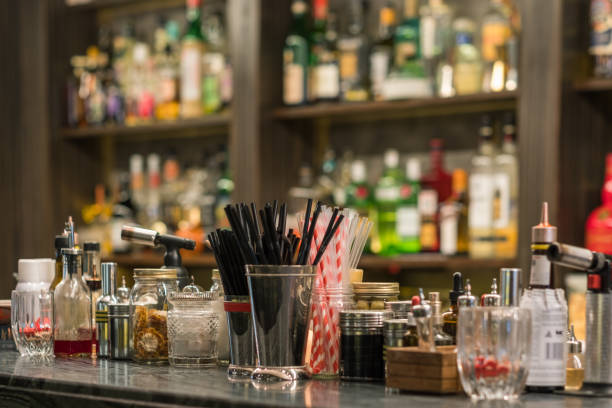 istock Professional Cocktail Tools And Ingredients In Glass Bottles And Jars For Creative Modern Fashionable Cocktails On Wooden Bar Counter. Blurred Bottles With Alcoholic Drinks On Background. 1011751518