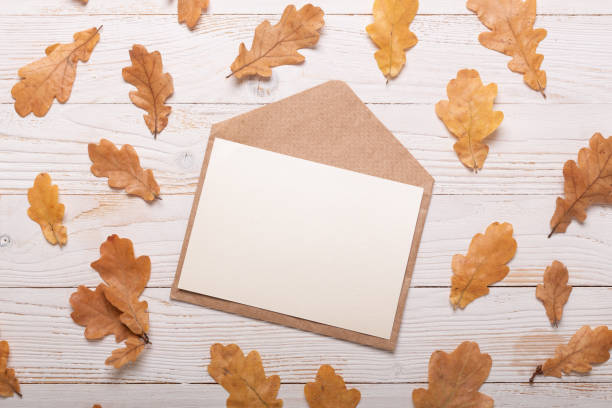 istock Autumn leaves and envelope on a white wooden background 1011751612