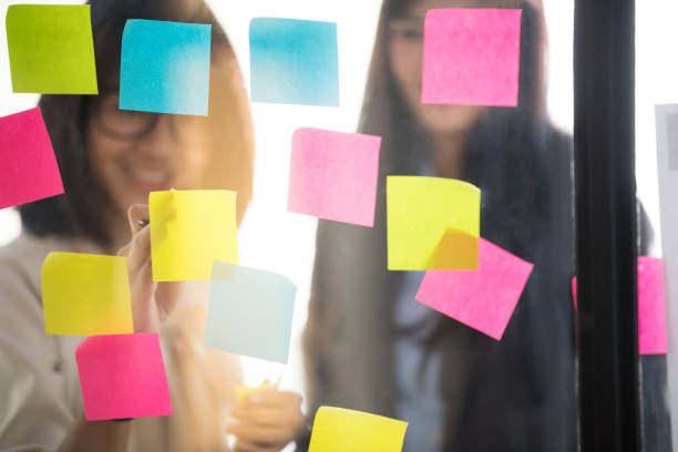 istock Businesspeople putting their ideas at sticky notes on window. 1011762286