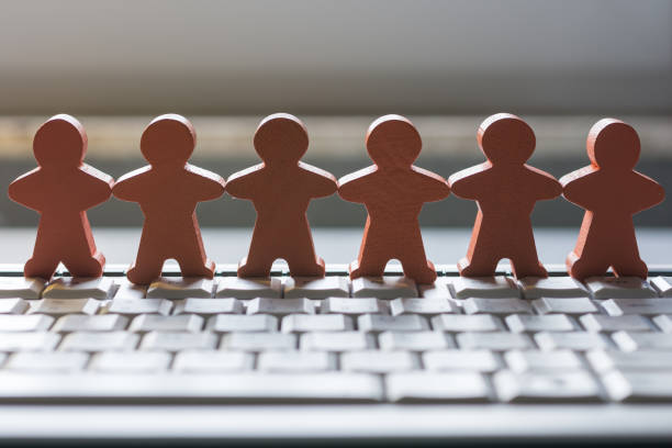 istock Wooden figures hand in hand on a computer keyboard in an office 1011773012