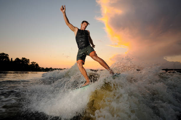 istock Athletic man wakesurfing down the river waves 1011776234