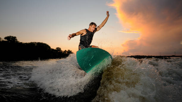 istock Handsome man wakesurfing down the river waves 1011776346
