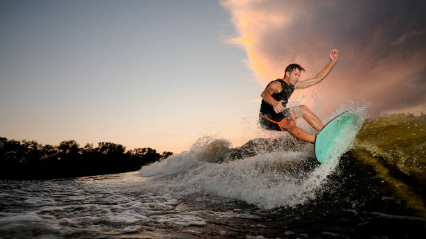 istock Handsome muscular young man wakesurfing down the river waves 1011776410