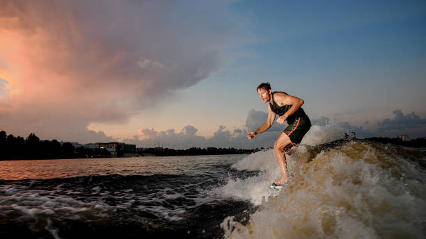 istock Athletic man riding on wake surf down the river during sunset 1011776588