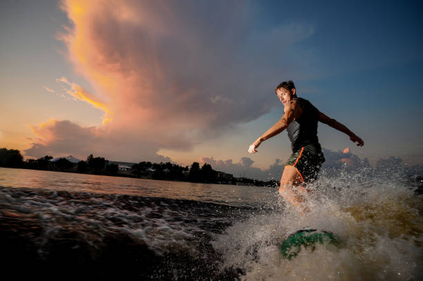 istock Young and athletic man riding on wake surf down the river during sunset 1011776804