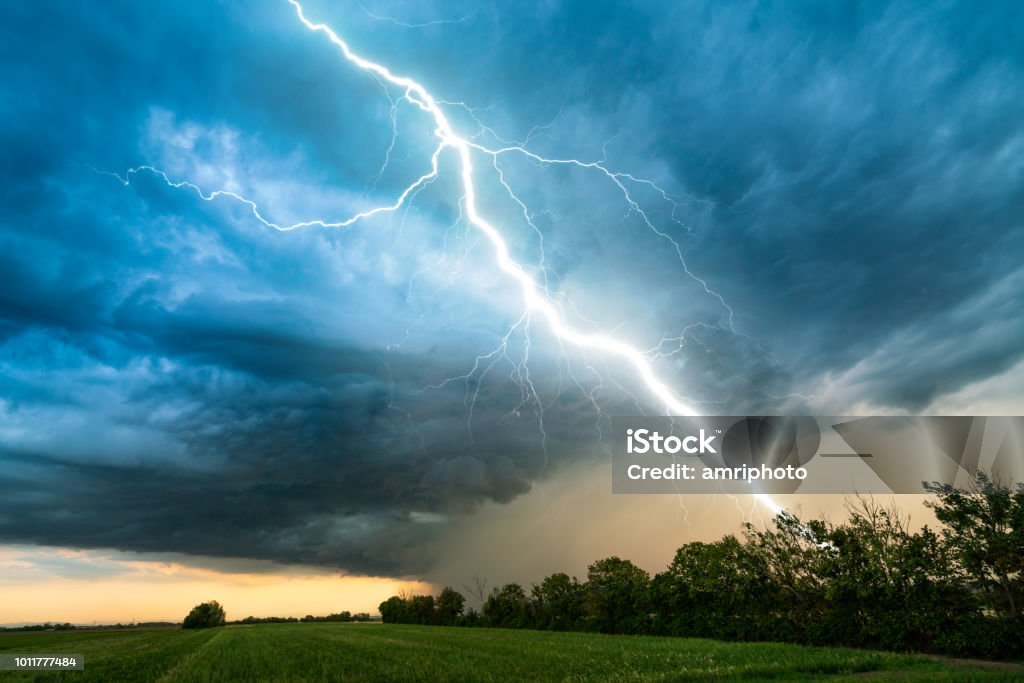cloud storm sky with thunderbolt over rural landscape dramatic lightning thundertbolt bolt strike in daylight rural surrounding bad weather dark sky Lightning Stock Photo