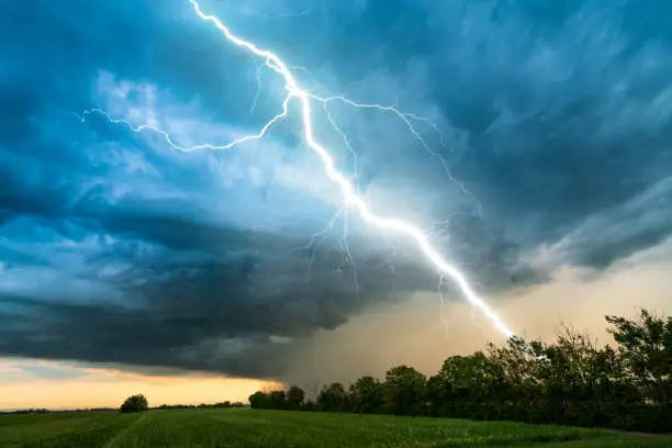Photo of cloud storm sky with thunderbolt over rural landscape
