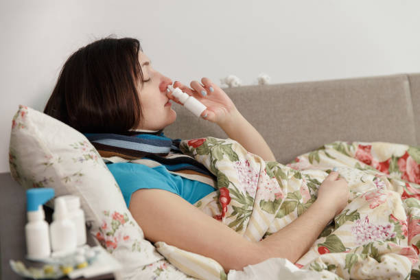 istock Sick woman lying in bed at home, spray in nose 1011781864