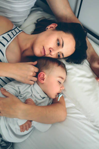 istock Man with wife watching his sleeping son 1011789468