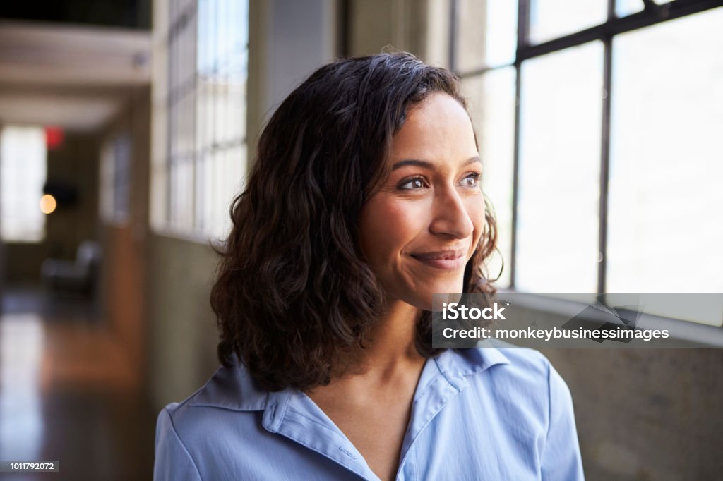Empresária de raça mista jovem sorridente a desviar o olhar - Foto de stock de Mulheres royalty-free