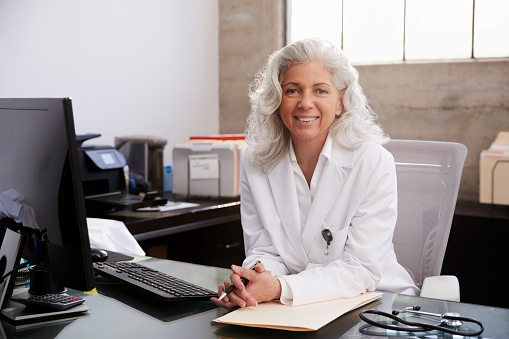 Senior femenino médico sentado en el escritorio en una oficina, retrato photo