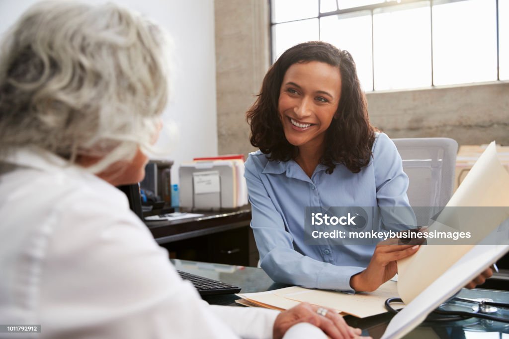 Analista donna sorridente in consultazione con donna anziana - Foto stock royalty-free di Sanità e medicina