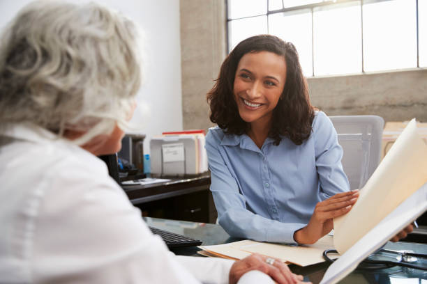 smiling female analyst in consultation with senior woman - concentration multi ethnic group meeting business imagens e fotografias de stock