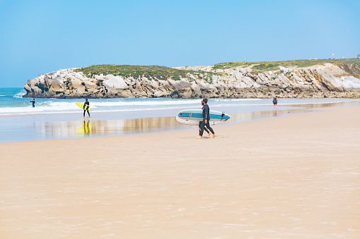 Surfers with surfboards walking along Baleal's beach near Peniche. Peniche is one of the best surfing destinations in Portugal. Choose from variety of surf spots in Peniche. There are waves for all kind of surfers.