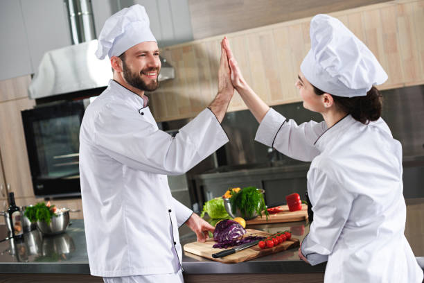 istock Professional team of cooks giving high five by kitchen counter 1011810200