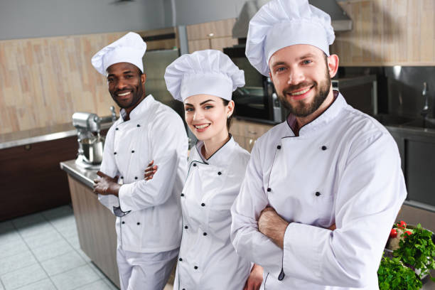 istock Multiracial team of cooks looking at camera by cooking table 1011810256