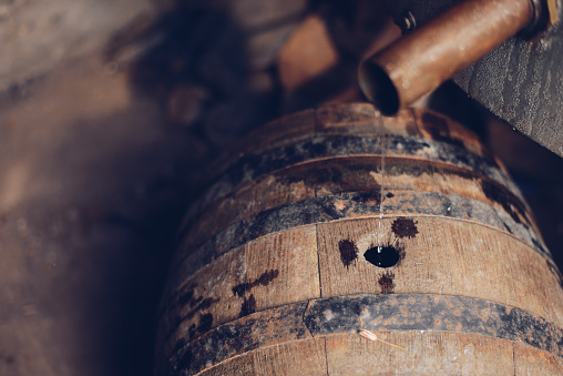 Moonshine Alcohol Flowing from the copper pipe to the old wooden barrel