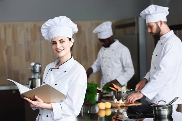 istock Female chef checking recipe in book by her multiracial colleagues 1011813116