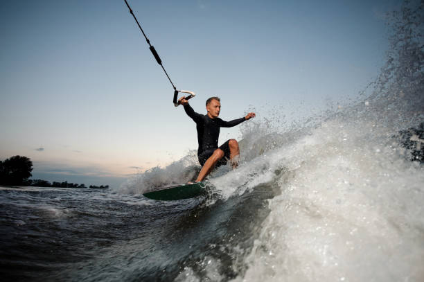 istock Active and young man riding on a wake board at the evening 1011814300