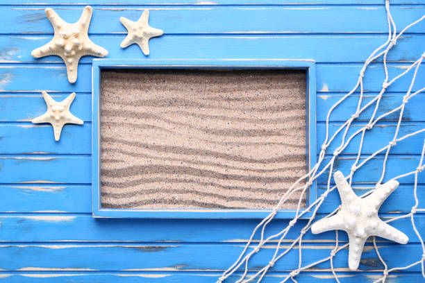 istock Blue wooden frame with starfishes on beach sand 1011816686