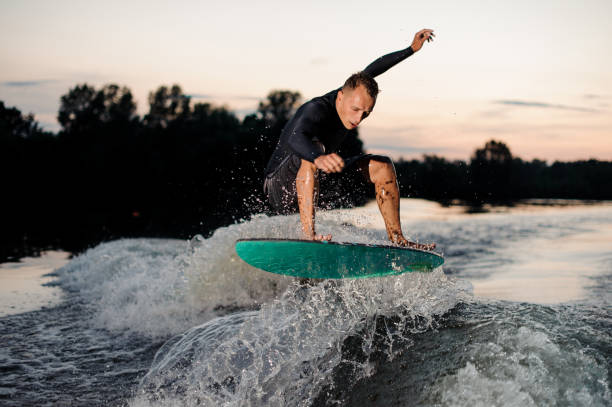 istock Young wakesurfer in black swimsuit jumping on a wake board 1011818952