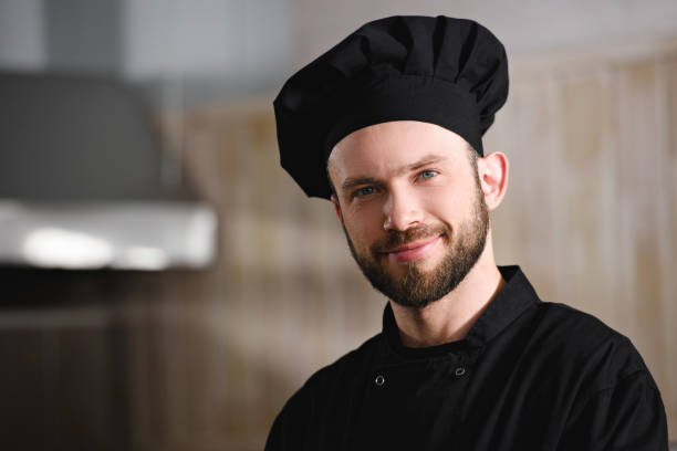 istock portrait of handsome chef in black uniform looking at camera at restaurant kitchen 1011819726
