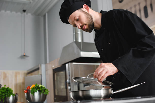 istock side view of handsome chef cooking with frying pan at restaurant kitchen 1011819810