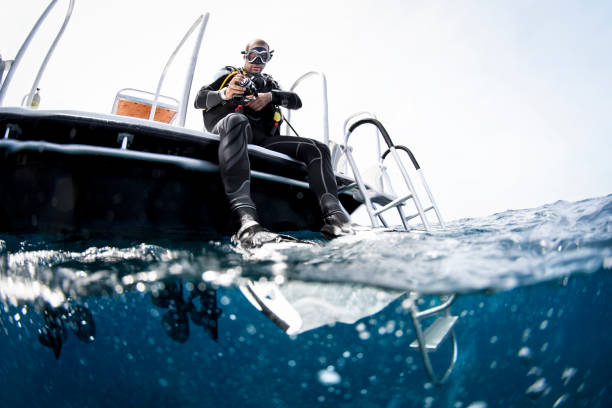 Scuba diving Scuba diver on the boat before diving in the Carrebbean sea near Cayman Islands. deep sea diving underwater underwater diving scuba diving stock pictures, royalty-free photos & images