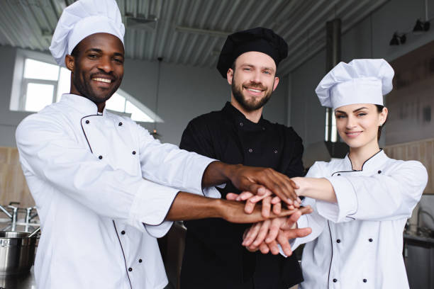 istock smiling multicultural chefs putting hands together at restaurant kitchen 1011819918