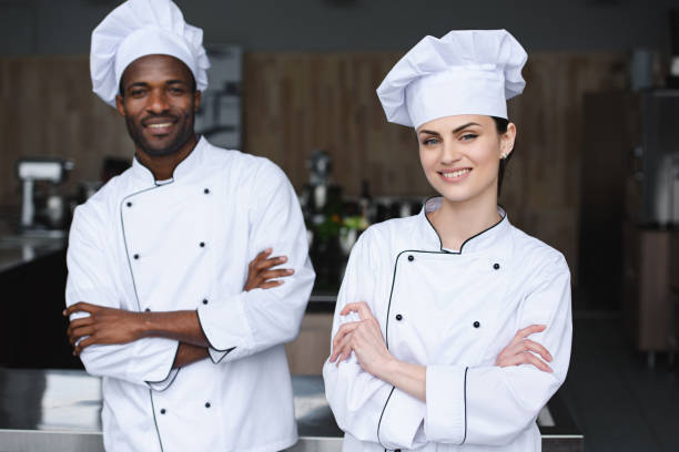 istock multicultural chefs standing with crossed arms and looking at camera at restaurant kitchen 1011820068