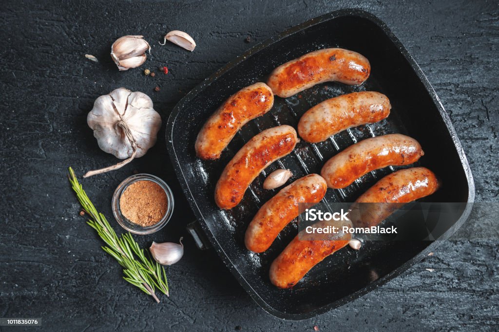 Vue de dessus sur frites saucisses dans une poêle noire sur une table en pierre noire - Photo de Saucisse libre de droits