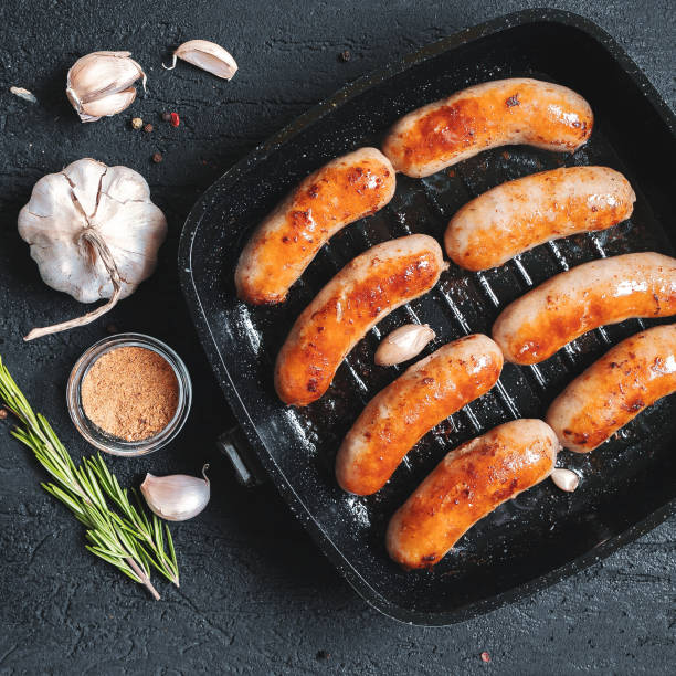 Top view on fried sausages in a black frying pan on a black stone table stock photo