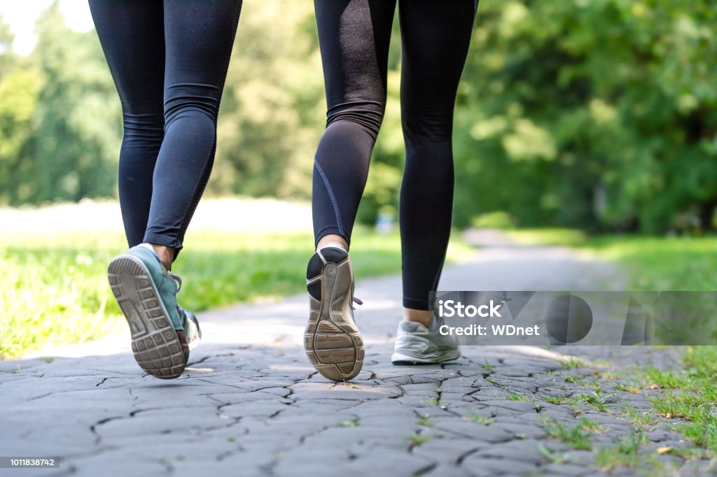 Female running feet in sport shoes Wellness and fitness concept - low angle view of running women in the park on a sunny morning. Walking Stock Photo