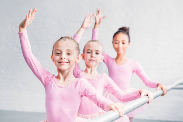 istock adorable multiethnic kids practicing ballet and smiling at camera in ballet studio 1011838862